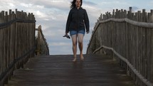 a woman walking over a boardwalk 
