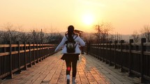 a teen girl running across a bridge 