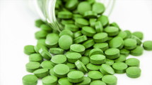 A spilt pill bottle of green pills 