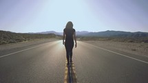 a woman walking in the middle of a road 