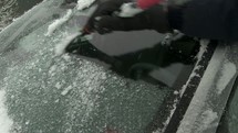 Scraping ice off o car windshield.
