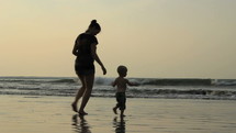 Mother and son running on the beach.