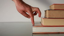 fingers walking up a stack of books 