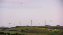 Moving wind turbines on grassy hills.