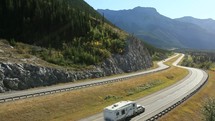 RV travelling on a highway through the mountains.