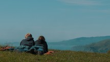 Couple laying in the grass on a mountain.