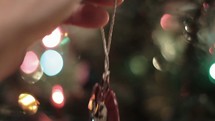 hanging an ornament on a Christmas tree 