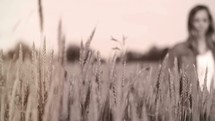 woman walking through a field of wheat