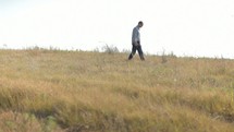 Man with a Bible walking through a field.