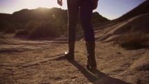 Person in boots walking through dirt in the desert.