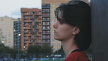 Side view of a woman at a park looking sad.