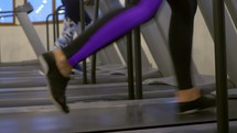 Two people jogging onn a treadmill.