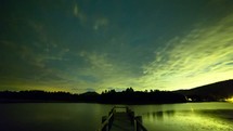Timelapse of a lake at night.  Showing setting moon and stars moving across the sky.  The milky way galaxy can be seen.  During the night, clouds roll in and eventually cover the starry sky.