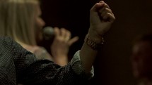 a woman singing into a microphone leading a worship service in song 