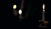 2 Shots - A slider shot of a row of people holding their lit candles during a candlelight Christmas Eve Service