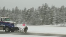 Snow plow truck on a highway in the winter.