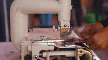 Woman putting a piece of leather through a machine 