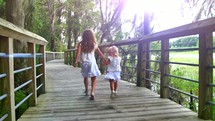 sisters running holding hands on a boardwalk 