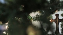 lights on a Christmas tree and a cross ornament 