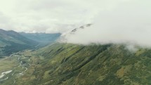clouds moving over green mountains