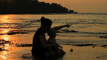 Mother and child on the beach at sunset.
