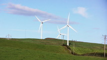 Moving wind turbines on a grassy hill.