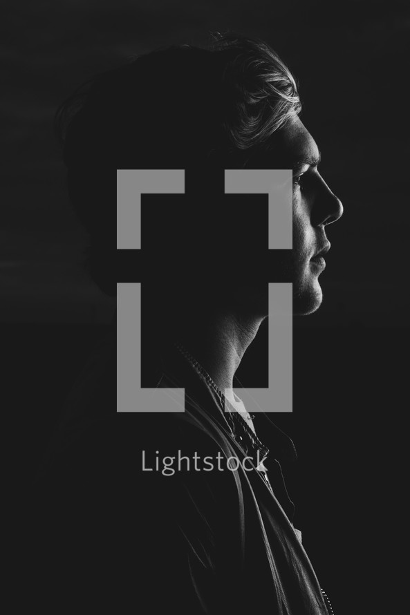 side profile of a young man in darkness 