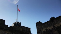Flag of the United Kingdom blowing in the wind at the top of a castle.