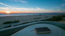 Timelapse of a bible on a bench overlooking  sunset at the beach. 