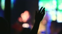 Silhouette of audience with raised hands worshipping at a concert.