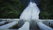 a man on a bridge looking down over a waterfall 