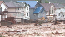 Flood waters rushing through a devastated community.