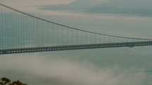 Traffic traveling across the Golden Gate Bridge over the misty ocean water.