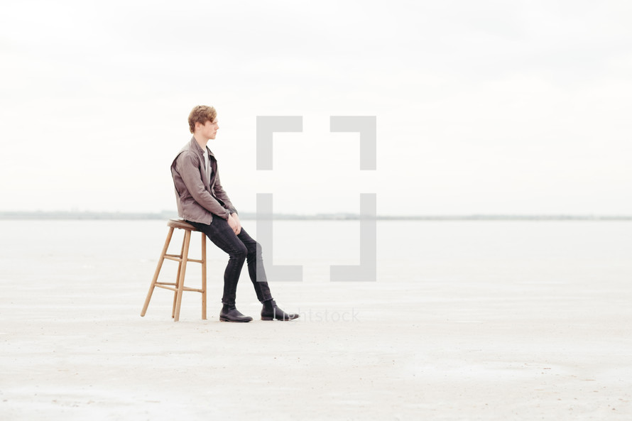 a man sitting on a stool on the great salt plains in Oklahoma 