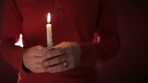 A man holding a flickering candle