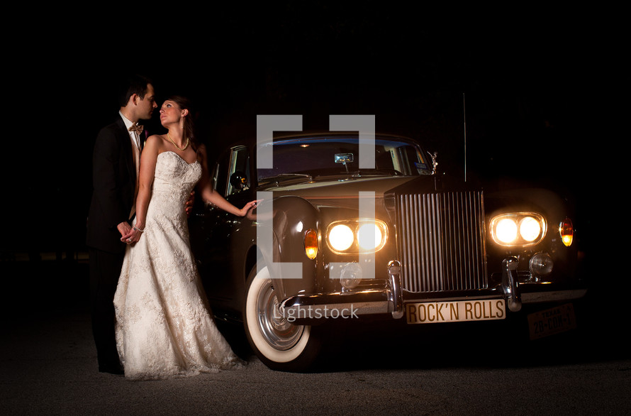bride and groom standing in front of a vintage rolls royce car