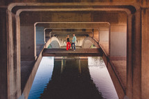 couple holding hands standing under a bridge