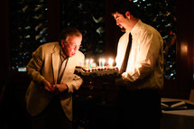 man blowing out the candles on a birthday cake