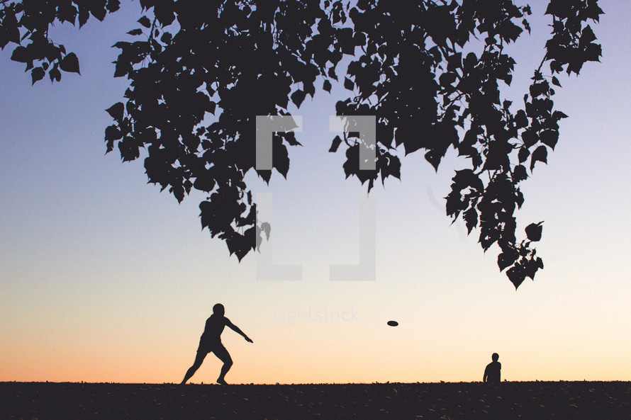 friends playing frisbee in a park 