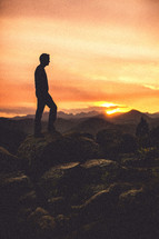 Man standing on rocks at sunset