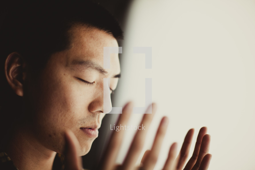 An Asian man worshipping with his palms open