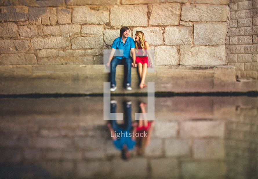 Couple sitting in front of stone wall holding hands
