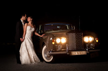 bride and groom standing in front of a vintage rolls royce car