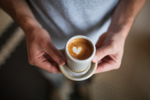 a man holding a coffee with heart shape creamer 