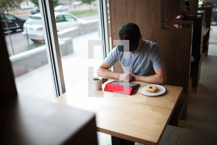 a man sitting in a window seating working at an iPad 