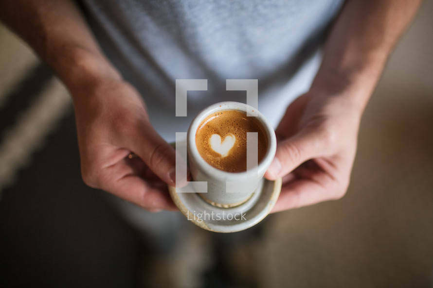 a man holding a coffee with heart shape creamer 