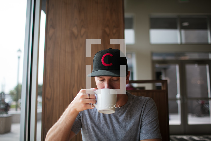 a man sitting in a window seat drinking coffee 