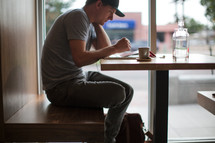 a man sitting in a window seat working on an iPad 