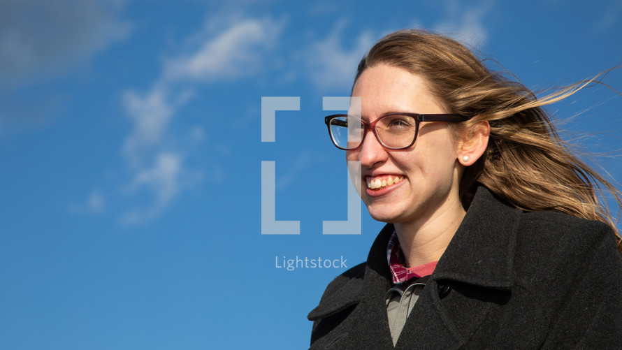 a young woman with glasses against a blue sky 