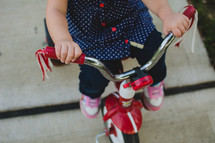 a toddler girl on a red tricycle 